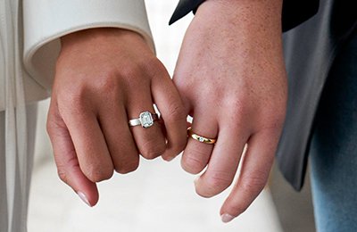 Two gender neutral models wearing rings, holding hands