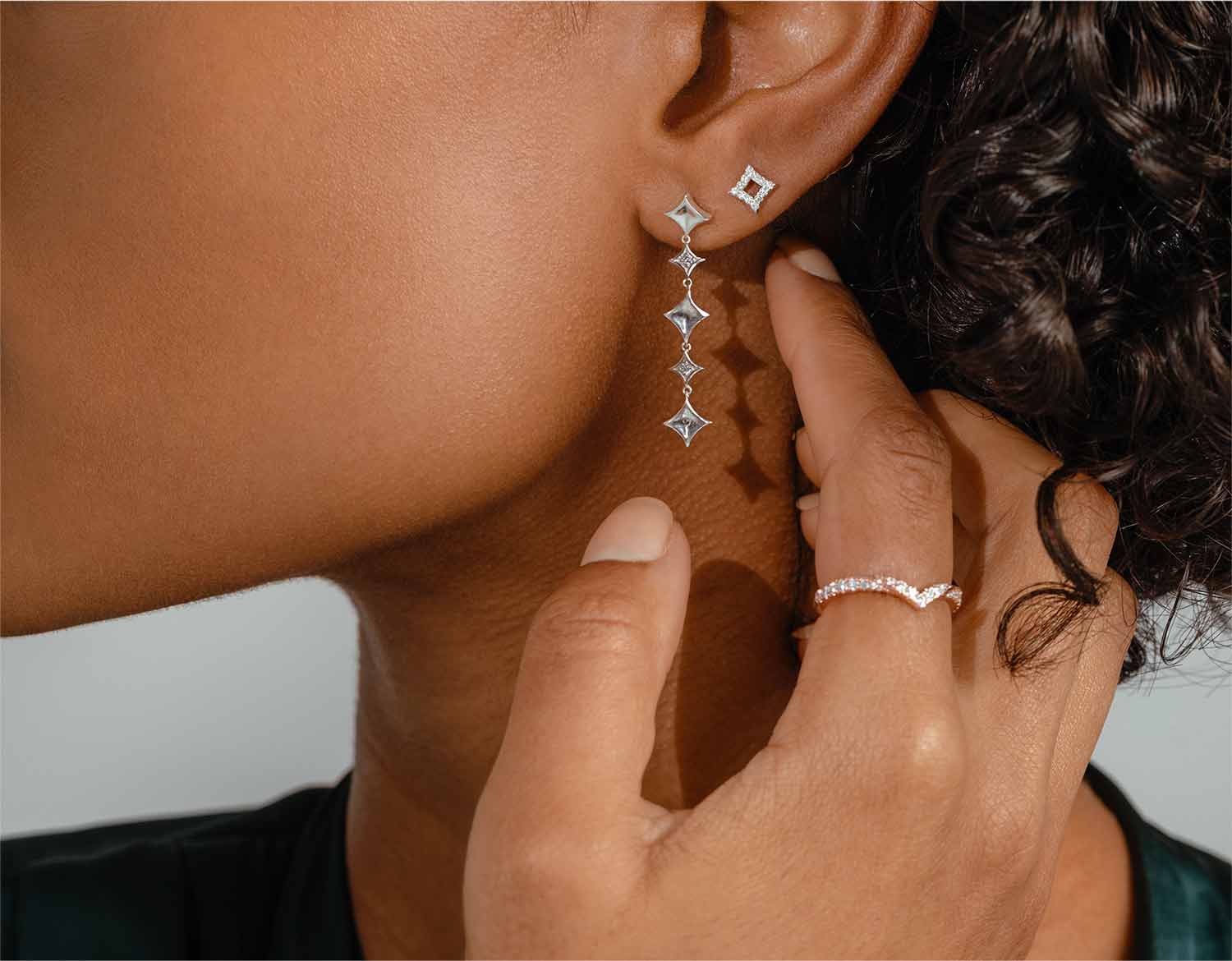 Woman wearing distinctive diamond earrings and chevron wedding ring