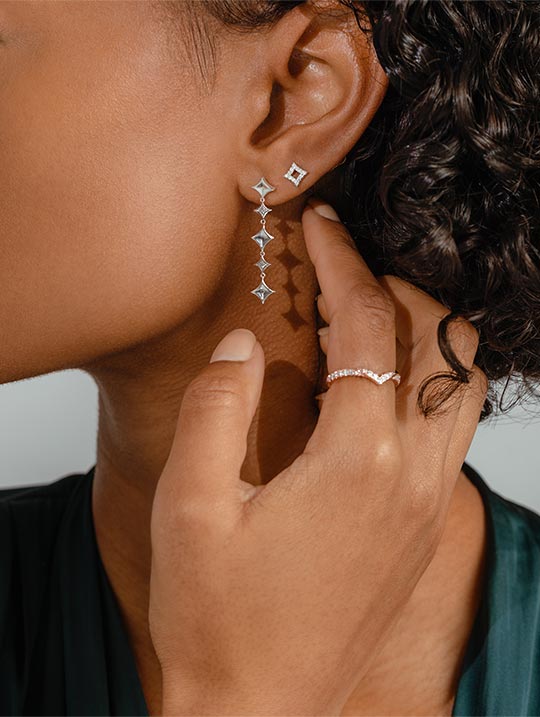 Woman wearing distinctive diamond earrings and chevron wedding ring