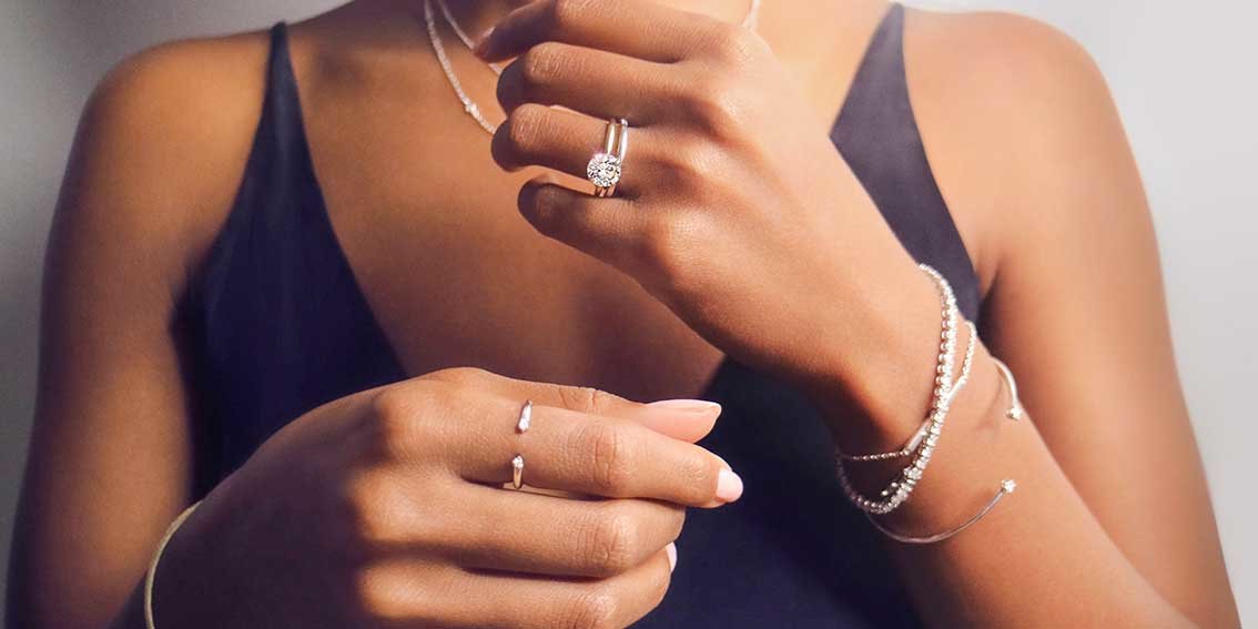 Woman wearing diamond rings, bracelets, and necklaces.