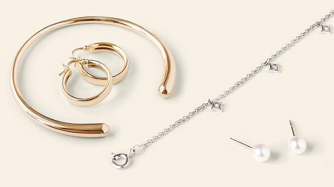 A gold bracelet, gold hoop earrings, diamond necklace, and pearl stud earrings.
