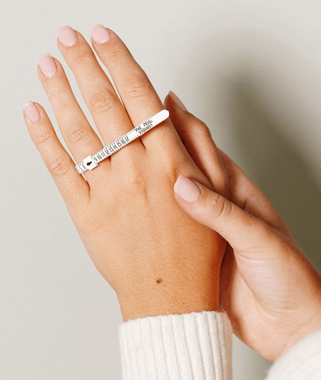 Womans hand wearing a ring sizer.