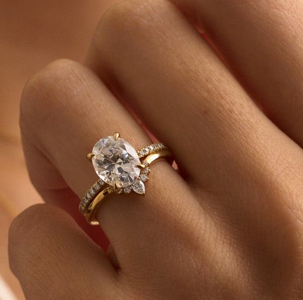 Model wearing gold diamond engagement ring and contoured, diamond wedding ring.