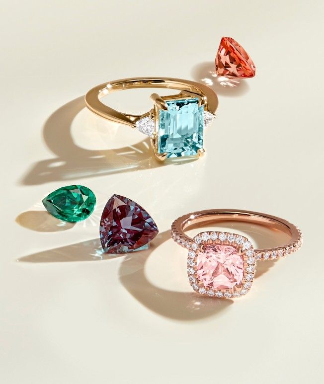 Assortment of gemstone engagement rings and loose gemstones.
