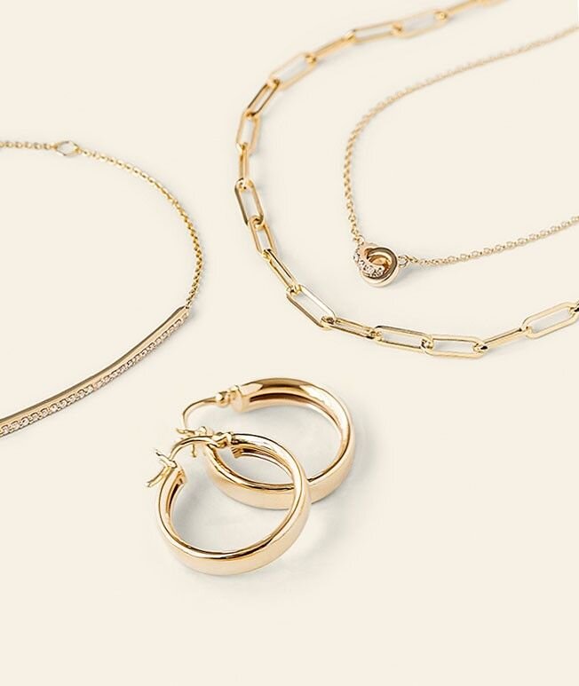 Variety of yellow gold jewelry, highlighting yellow gold hoop earrings, yellow gold necklace, and yellow gold bracelet.