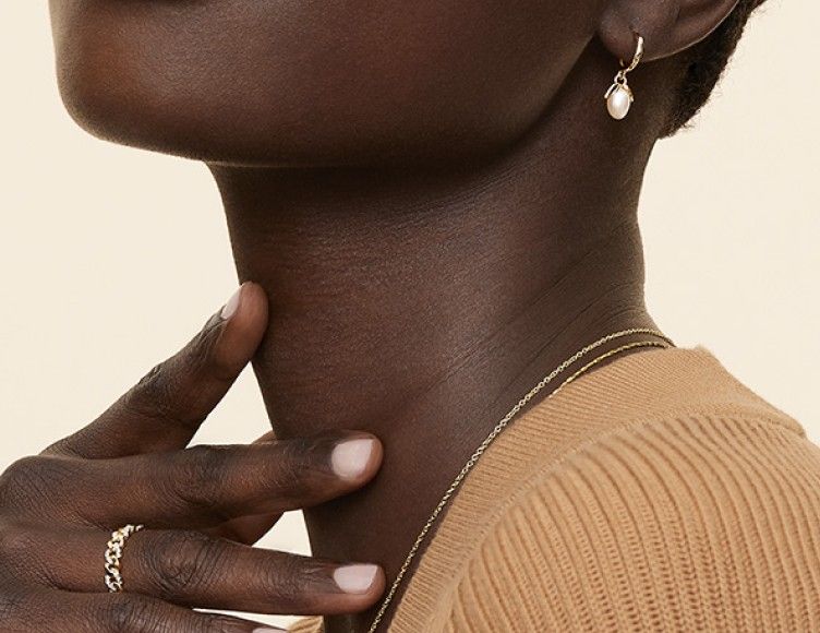 Model wearing pearl earrings, fashion ring and variety of necklaces.