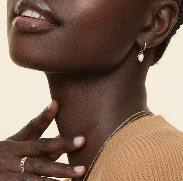 Model wearing pearl earrings, fashion ring and variety of necklaces.