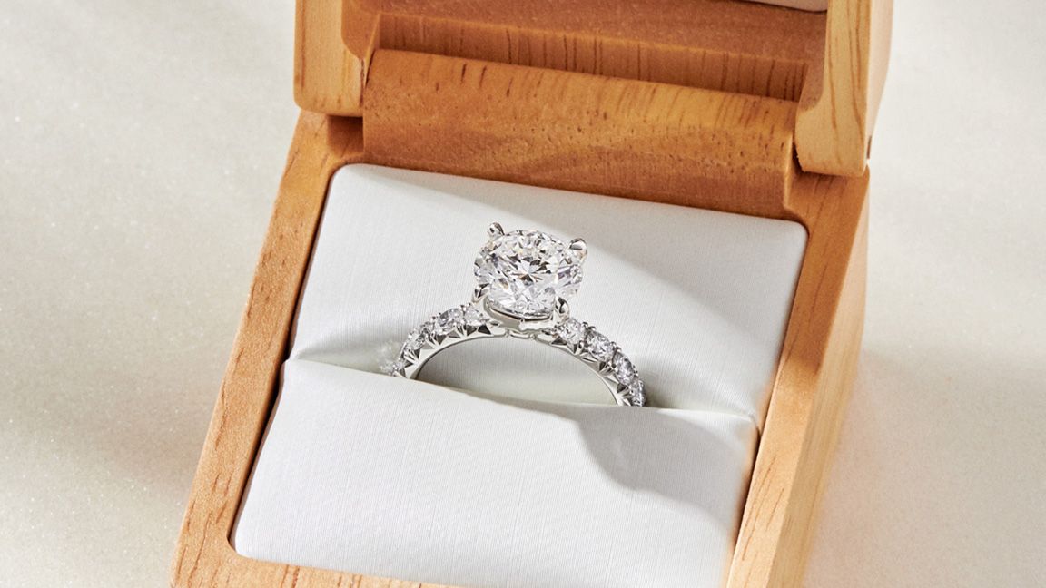 White gold engagement ring inside wooden jewelry box.