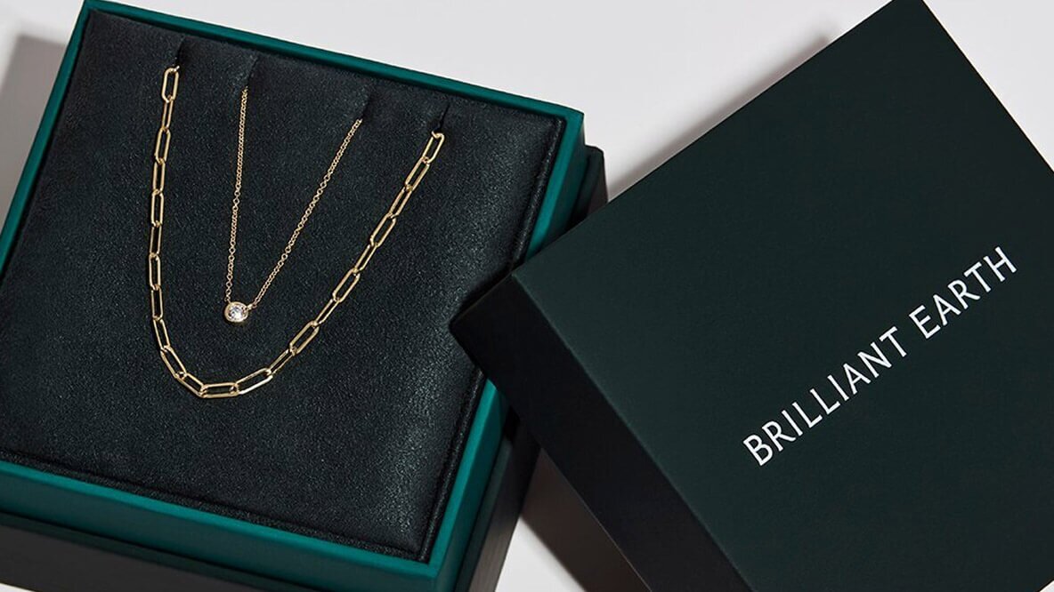 Women's yellow gold diamond pendant and paperclip chain inside a jewelry box.