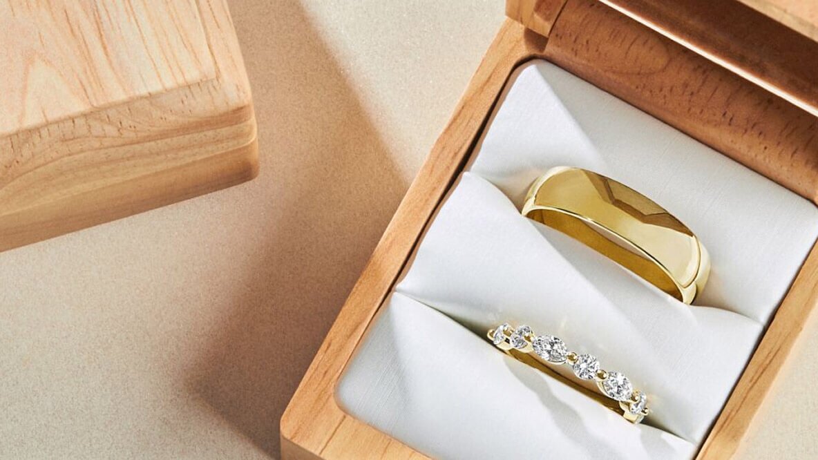 Men’s and Women’s yellow gold wedding bands in a wooden ring box.