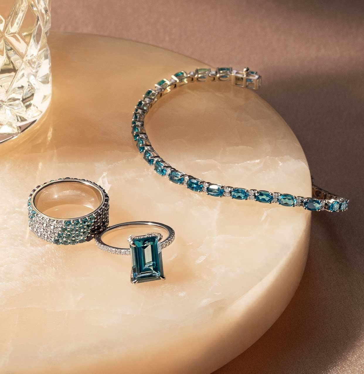 Assortment of gemstone jewelry, featuring gemstone rings, and a gemstone bracelet.